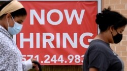 FILE - Women walk past by a 'Now Hiring' sign outside a store in Arlington, Virginia, Aug. 16, 2021.. 