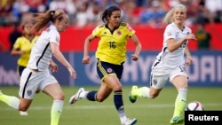 Colombia forward Lady Andrade (16) moves the ball against United States defender Becky Sauerbrunn (4) and defender Julie Johnston (19) during the second half in the round of sixteen in the FIFA 2015 women's World Cup soccer tournament at Commonwealth Stad