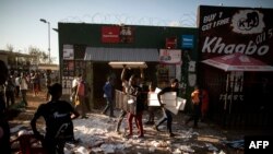 FILE - Looters take items from a foreign-owned shop in Soweto, Johannesburg, Aug. 29, 2018, during unrest that erupted after a foreign shop owner allegedly shot and killed a member of the community during a demonstration.