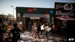 FILE - Looters take items from a foreign-owned shop in Soweto, Johannesburg, Aug. 29, 2018, during unrest that erupted after a foreign shop owner allegedly shot and killed a member of the community during a demonstration.