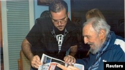 Sou foto sa a, ki sòti nan Cubadebate, ansyen prezidan kiben Fidel Castro (ki gen 88 tan) ak prezidan Federasyon Etidyan Inivèsitè Kiben yo, Randy Perdomo, ap gade yon jounal pandan yon rankont nan La Avàn. 