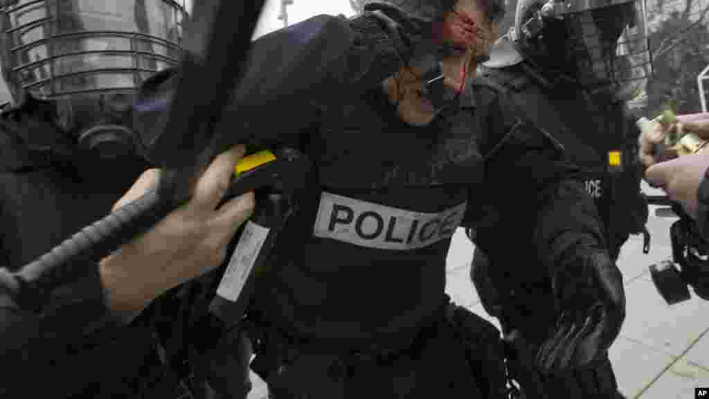 Un policier blessé est aidé par des collègues lors d&#39;une manifestation dans la capitale du Kosovo Pristina. Police au Kosovo a tiré des gaz lacrymogènes sur des milliers de manifestants anti-gouvernementaux exigeant la démission d&#39;un ministre.