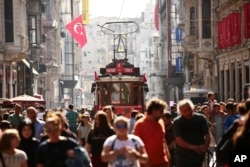 FILE - People walk in central Istanbul's Istiklal Avenue, the ancient city's main shopping street, Aug. 22, 2018.