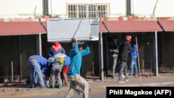 Un homme porte sur la tête un réfrigérateur qui a été pillé dans un centre commercial du township de Katlehong, à l'est de Johannesburg, le 12 juillet 2021. (photo d'archives). 