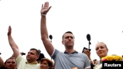 Russian protest leader Alexei Navalny (2nd R) and his co-defendant Pyotr Ofitserov (2nd L), stand near their wives, surrounded by supporters and journalists, after arriving from Kirov at a railway station in Moscow, July 20, 2013. 