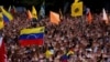 Anti-government protesters hold their hands up during the symbolic swearing-in of Juan Guaido, head of the opposition-run congress who declared himself interim president of Venezuela during a rally demanding President Nicolas Maduro's resignation in Carac