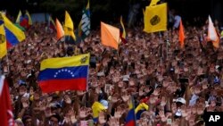 Anti-government protesters hold their hands up during the symbolic swearing-in of Juan Guaido, head of the opposition-run congress who declared himself interim president of Venezuela during a rally demanding President Nicolas Maduro's resignation in Carac