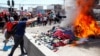 Manifestantes queman las pertenencias de migrantes venezolanos en un campamento improvisado en una plaza pública durante una manifestación contra la migración en Iquique, Chile, 25 de septiembre de 2021. 