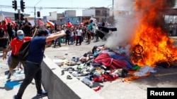 Manifestantes queman las pertenencias de migrantes venezolanos en un campamento improvisado en una plaza pública durante una manifestación contra la migración en Iquique, Chile, 25 de septiembre de 2021. 