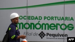 ARCHIVO - Un trabajador camina junto a un cartel de la empresa venezolana de fertilizantes Monómeros, en Barranquilla, Colombia, el 9 de octubre de 2021.