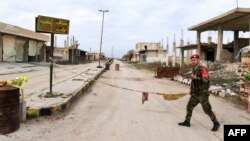 Seorang tentara Suriah tampak berjalan di dekat papan nama kota Saraqeb yang berhasil direbut pasukan Suriah dari pemberontak. 