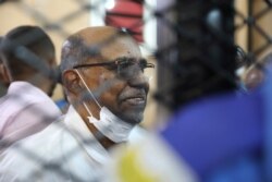 FILE - Sudan's ousted president Omar al-Bashir sits at the defendant's cage during his trial a courthouse in Khartoum, Sudan, Sept. 15, 2020.