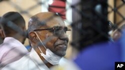 FILE - In this Sept. 15, 2020, photo, Sudan's ousted president, Omar al-Bashir, sits at the defendant's cage during his trial in a courthouse in Khartoum, Sudan, Sept. 15, 2020.