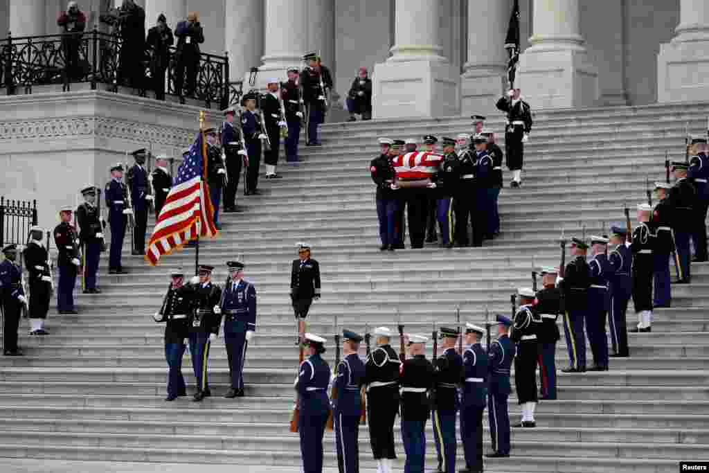 The flag-draped casket of former President George H.W. Bush is carried by a joint services military honor guard from the U.S. Capitol, Dec. 5, 2018, in Washington.