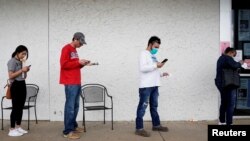 FILE - People who lost their jobs wait in line to file for unemployment at a Workforce Center in Fayetteville, Arkansas, April 6, 2020.