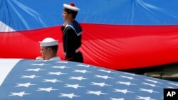 Tentara Prancis dan AS memajang bendera nasional mereka di akhir parade militer Hari Bastille di Champs Elysees di Paris, Prancis, Jumat, 14 Juli 2017. (Foto: AP/Michel Euler)