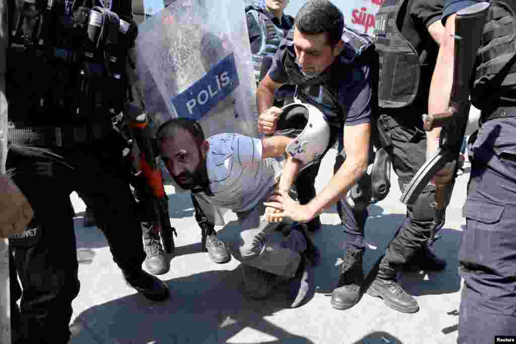 Riot police detain a demonstrator during a protest against the suspension of teachers from classrooms over alleged links with Kurdish militants, in the southeastern city of Diyarbakir, Turkey.