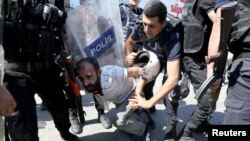 FILE - Riot police detain a demonstrator during a protest against the suspension of teachers from classrooms over alleged links with Kurdish militants, in the southeastern city of Diyarbakir, Turkey, Sept. 9, 2016. 