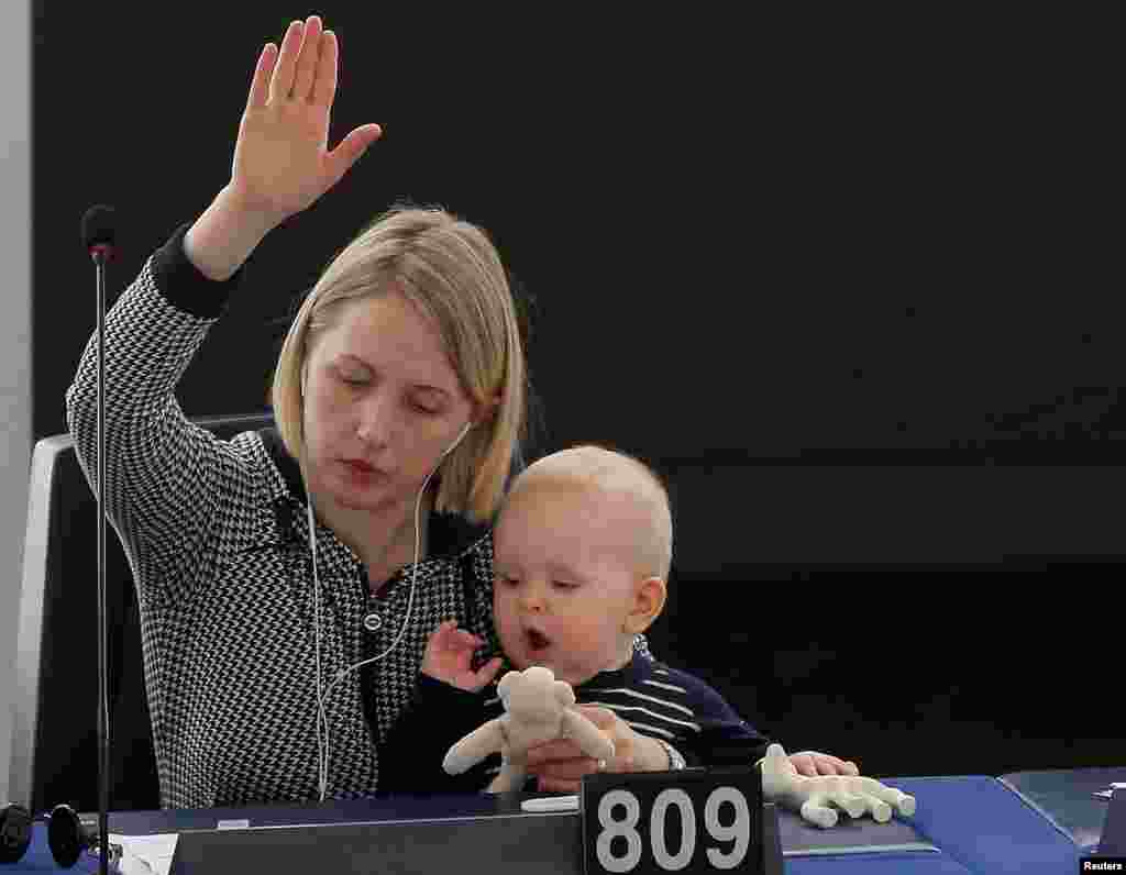 Seorang anggota parlemen Eropa dari Swedia Jytte Guteland menggendong bayinya sambil memberikan suara pada sesi voting Parlemen Eropa di Strasbourg, Perancis.