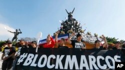 Para pengunjuk rasa mengepalkan tinju mereka sambil membentangkan banner hitam sebagai bagian dari aksi protes pemakaman diktator Ferdinand Marcos di taman makam pahlawan tahun lalu, di kota Mandaluyong pinggiran kota, timur laut Manila, Filipina, menandai ulang tahun ke-31 pemberontakan dalam upaya menggulingkan Marcos dari 20 tahun berkuasa di negara tersebut, Sabtu, 25 Februari 2017. (AP Photo/Bullit Marquez)
