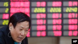 An investor talks in front of the stock price monitor at a private securities company in Shanghai, China, Nov. 25, 2013. (AP)
