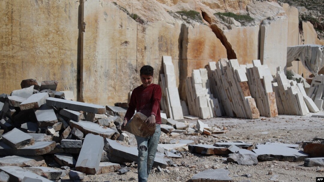 Aqeel Othman, seorang anak pengungsi Suriah berusia 13 tahun, membawa balok batu di tambang tempatnya bekerja di pinggiran al-Dana, Provinsi Idlib, wilayah barat laut yang dikuasai pemberontak, pada 14 Maret 2024. (Foto: AFP)