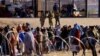 Migrants stand near the border wall after crossing the Rio Bravo river with the intention of turning themselves in to the U.S. Border Patrol agents, as seen from Ciudad Juarez, Mexico, April 14, 2023. 