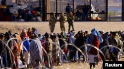 Migrants stand near the border wall after crossing the Rio Bravo river with the intention of turning themselves in to the U.S. Border Patrol agents, as seen from Ciudad Juarez, Mexico, April 14, 2023. 