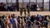 Los migrantes esperan cerca del muro fronterizo después de cruzar el río Bravo con la intención de entregarse a los agentes de la Patrulla Fronteriza de Estados Unidos, visto desde Ciudad Juárez, México, el 14 de abril de 2023.
