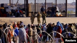 Los migrantes esperan cerca del muro fronterizo después de cruzar el río Bravo con la intención de entregarse a los agentes de la Patrulla Fronteriza de Estados Unidos, visto desde Ciudad Juárez, México, el 14 de abril de 2023.