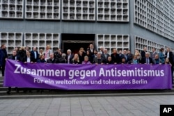 Warga dan politisi membentangkan spanduk bertuliskan "bersama melawan antisemitisme, demi Berlin yang berpikiran terbuka dan toleran" di luar gereja peringatan Kaiser Wilhelm di Berlin, Jerman, 7 Oktober 2024, menandai satu tahun serangan 7 Oktober 2023.(Markus Schreiber/AP)