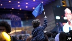 A young boy waves an EU flag as he watches a giant screen television outside the European Parliament in Brussels, Belgium, May 26, 2019.