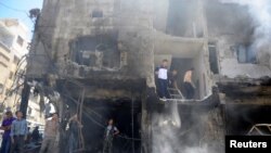 People and Syrian Army members inspect a damaged site after a suicide and car bomb attack in south Damascus Shi'ite suburb of Sayyida Zeinab, Syria, June 11, 2016. 