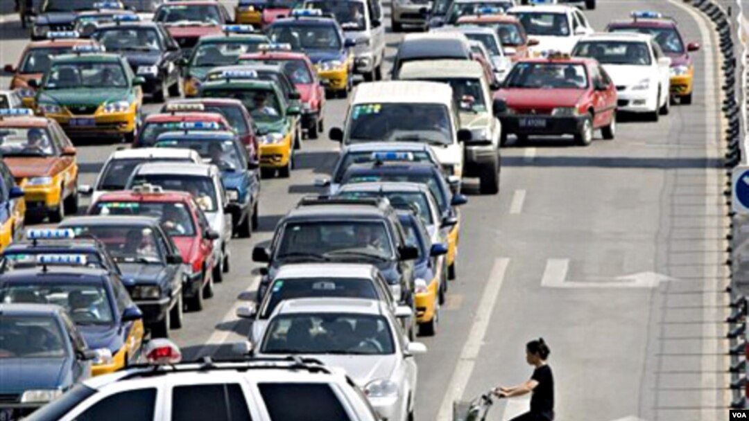 Seorang pengendara sepeda di Beijing menembus kemacetan lalu-lintas. Jumlah kendaraan pribadi meningkat lebih cepat dibanding kapasitas jalan raya di Tiongkok.