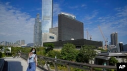 FILE - A woman walks outside the M+ visual culture museum in the West Kowloon Cultural District of Hong Kong, Nov. 11, 2021.