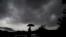 FILE - A villager holds an umbrella as dark clouds loom over Balasore district, in India, May 25, 2021, ahead of a powerful storm. When it comes to measuring global warming, it’s not just the heat, it’s the humidity that matters in climate extremes.