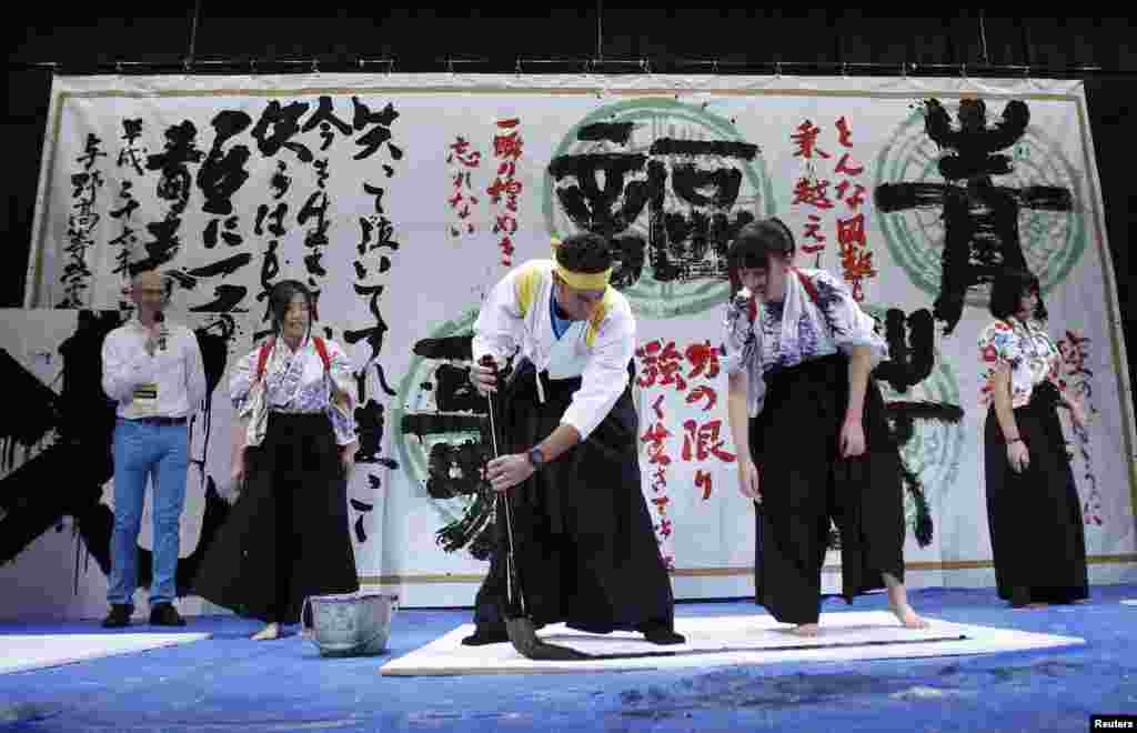 Astana team rider and Tour de France winner Vincenzo Nibali of Italy dressed in a hakama writes the Chinese character of &quot;King&quot; with a giant brush during a calligraphy performance, which is also an exchange event with local students, in Saitama, north of Tokyo. 