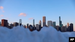 FILE - The Chicago skyline is visible Feb. 1, 2021, over heaps of snow dumped after a weekend-long winter storm hit the city. The present December 22, 2022 winter storm is expected to produce significant snowfall, even blizzards, over a wide part of the nation.. 