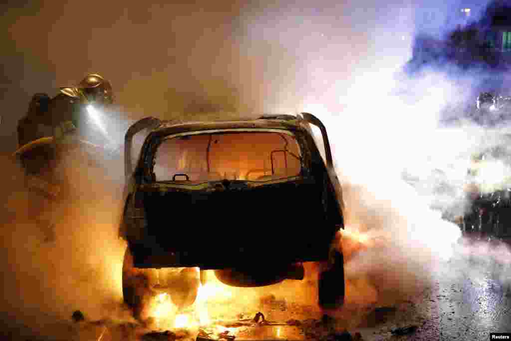 Firefighters extinguish a burning car during New Year's eve celebrations in Lille, France, Dec. 31, 2013.