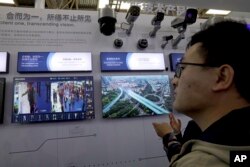 FILE - A man looks at technologies from state-owned surveillance equipment manufacturer Hikvision on a monitor at a Security China 2018 expo in Beijing, Oct. 23, 2018.