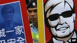 Police officer between images of blind Chinese activist Chen Guangcheng at protest, Hong Kong, May 4, 2012.
