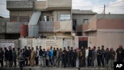 Iraqi civilians line up to receive food supplies in a neighborhood recently liberated by Iraqi security forces in western Mosul, March 14, 2017. 