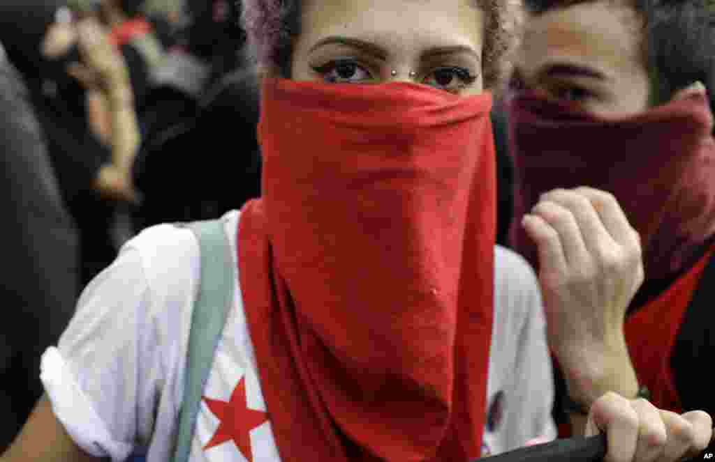 A demonstrator with her face covered marches during a protest on the route of the Olympic torch against the money spent on the Rio's 2016 Summer Olympics, in Niteroi, Brazil, Tuesday, Aug. 2, 2016. The three-month torch relay across Brazil will end at the opening ceremony on Aug. 5, in Rio de Janeiro's Maracana stadium. (AP Photo/Leo Correa)