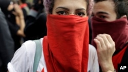A demonstrator with her face covered marches during a protest on the route of the Olympic torch against the money spent on the Rio's 2016 Summer Olympics, in Niteroi, Brazil, Tuesday, Aug. 2, 2016.