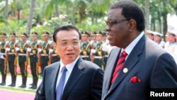 FILE - China's Premier Li Keqiang, left, talks to Namibia's Prime Minister Hage Geingob as they inspect an honor guard during a welcoming ceremony in Sanya, Hainan province, April 9, 2014. 