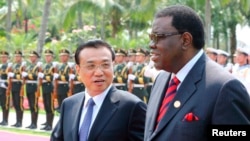 FILE - China's Premier Li Keqiang, left, talks to Namibia's Prime Minister Hage Geingob as they inspect an honor guard during a welcoming ceremony in Sanya, Hainan province, April 9, 2014. 