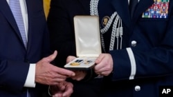 FILE - A military aide hands a Presidential Citizens Medal, the nation's second-highest civilian honor, to President Joe Biden during a ceremony in the East Room of the White House in Washington, Jan. 6, 2023. 