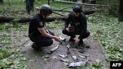 دو مأمور پلیس اوکراین در حال وارسی قطعات یک موشک که در پارک مرکزی شهر سقوط کرده است. خارکیف، اوکراین – ۳۱ اردیبهشت ۱۴۰۳ عکس از خبرگزاری فرانسه