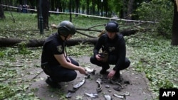 Ukrainian police officers examine fragments of a missile in the central park of Kharkiv on May 19, 2024, amid the Russian invasion in Ukraine.