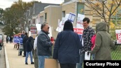 Lowell residents stand by a polling station with banners supporting their candidates on election day in Lowell, Massachusetts, November 7, 2017. (Courtesy photo of Sidney Liang)